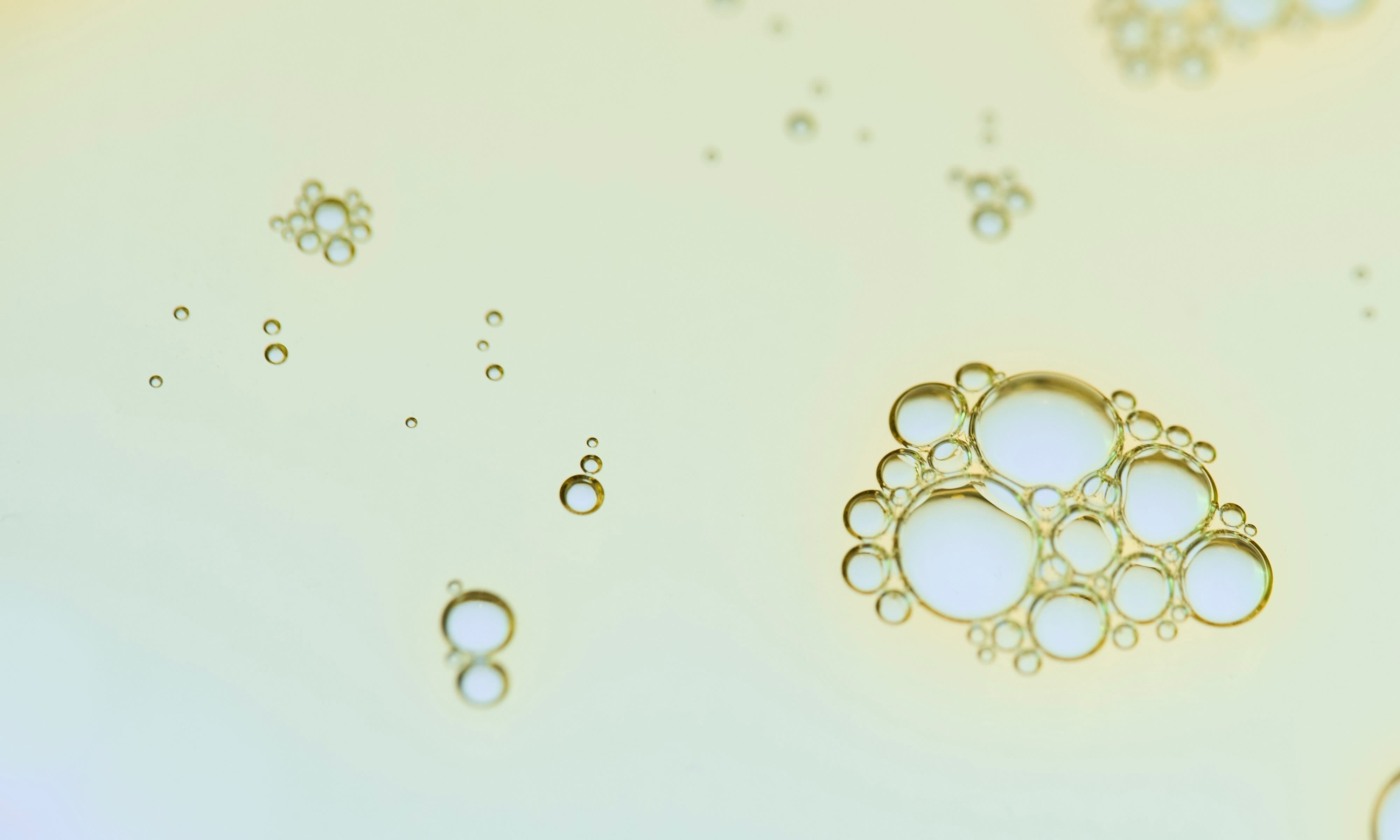 POM Care Co close-up scientific macro shot of a liquid surface with scattered bubbles.