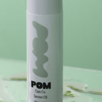 POM Saviour Oil bottle displayed against a soft green background.