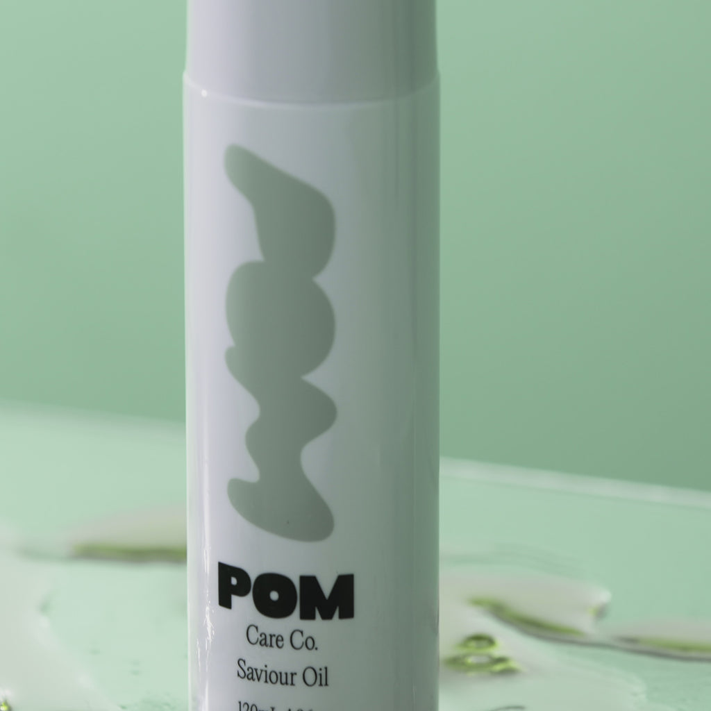 POM Saviour Oil bottle displayed against a soft green background.